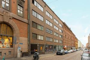 a large brick building on a city street with parked cars at Scandinavian Home 1BR Unbeatable Central Location 26 in Helsinki