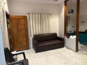 a living room with a leather couch and a wooden door at PuMi Residence in Vānivilāsa Puram