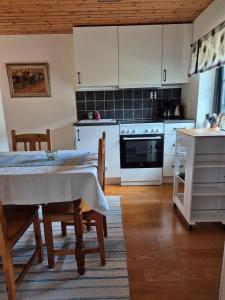 a kitchen with white cabinets and a table with chairs at Skånelänga nära Österlen in Vollsjö +10 photos