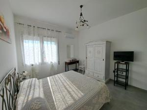 a white bedroom with a bed and a television at CENTRAL ROOMS TORTOLI' in Tortolì