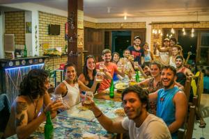 a group of people sitting around a table with wine glasses at Paraíso Hostel Praia do Rosa in Praia do Rosa