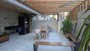 a patio with a table and chairs and a kitchen at Studio Aconchegante 200m praia Pajuçara e P Verde in Maceió
