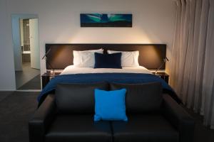 a bedroom with a bed and a couch with a blue pillow at Aurora on George in Dunedin