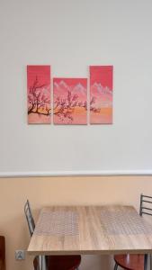a table with four paintings on the wall at Hostel Koral in Szczecin