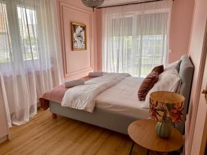 a bedroom with a large bed with pink walls and windows at Notting Hill Apartament in Rzeszów