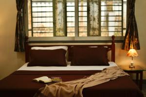 a bedroom with a bed with a window and a book at Jingle villa in Panchgani
