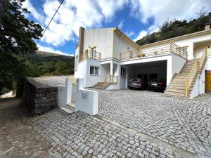a white house with a car garage and stairs at Casa das Oliveiras - Manteigas in Manteigas
