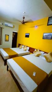 three beds in a room with yellow walls at New RPM Home Stay Gubera Nagar in Tiruvannāmalai