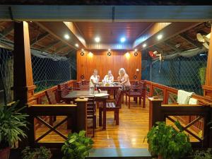 a group of people sitting at a table on a deck at Marari Xavier's Inn in Alleppey