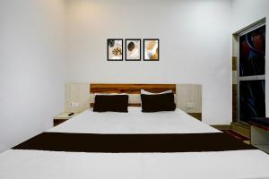 BilāspurにあるHotel O Pushkar And Restaurantの白いベッド1台、壁に3枚の絵が飾られたベッドルーム1室