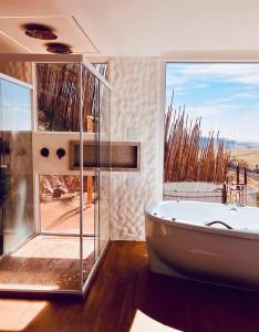 Un baño con bañera y una gran ventana. en Greece house blue, en Paty do Alferes