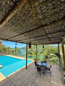 a patio with a table and chairs and a pool at Pousada Costa dos Corais in Mangaratiba