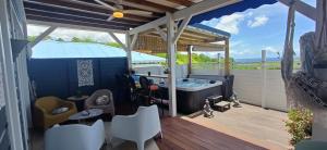 a porch with a hot tub on a deck at Gîtes Capra Pomme Surette piscine et spa in Bouillante