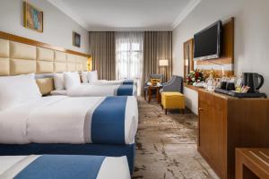 a hotel room with two beds and a flat screen tv at Emaar Elite Al Madina Hotel in Medina