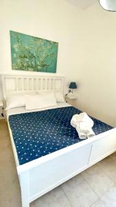 Una cama blanca en un dormitorio con una colcha azul. en Villa AlbeAle, en Torre Santa Sabina