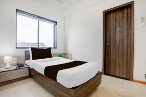 a bedroom with a large bed and a large window at Hotel O Metro in Rajkot