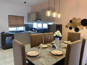 Una mesa de comedor con sillas y una cocina. en Santorini Meraki Villas, en Negombo
