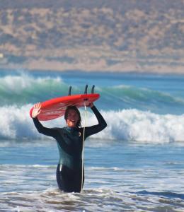 Una mujer en el océano con una tabla de surf en la cabeza. en calma palace, en Agadir