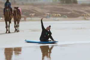 una persona sentada en una tabla de surf en la playa en calma palace, en Agadir