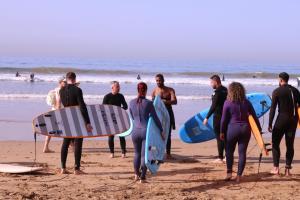 un grupo de personas de pie en la playa con tablas de surf en calma palace, en Agadir