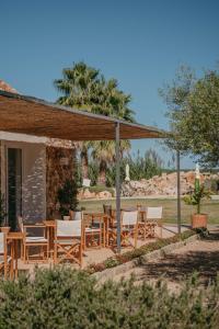 un patio con mesas y sillas de madera frente a una casa en Agroturismo Ses Talaies, en Ciutadella