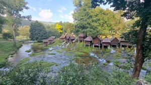 a group of huts next to a river with trees at Apartman Mila 2 in Jajce +12 photos