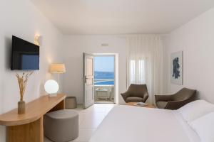 a white hotel room with a bed and a desk and chair at Lilium Hotel Santorini in Fira