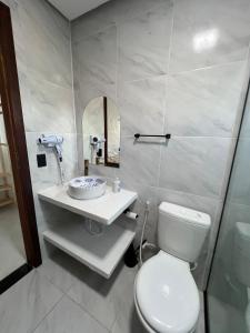 a bathroom with a white toilet and a sink at Casa Branca Mediterrânea in Barra Grande