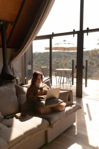a woman sitting on a couch with a laptop at Kos Hytte in Rio Acima