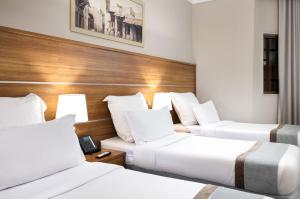 two beds in a hotel room with white pillows at Emaar Al Mektan Hotel in Medina +76 photos