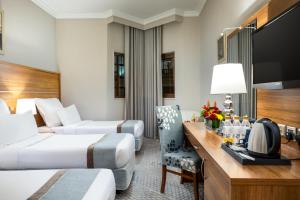 a hotel room with two beds and a desk at Emaar Al Mektan Hotel in Medina