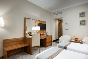 a hotel room with two beds and a desk at Emaar Al Mektan Hotel in Medina