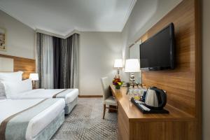 a hotel room with a bed and a flat screen tv at Emaar Al Mektan Hotel in Medina