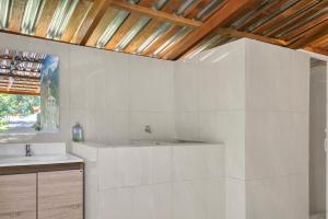 サンタ・アナにあるCozy Bedroom in a coffee farmn in Coatepeque Lakeの洗面台と木製の天井を備えた白いバスルーム