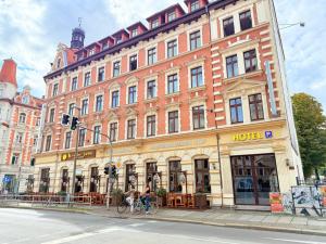 a large building on the corner of a street with people on a bike at Hotel Merseburger Hof in Leipzig