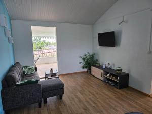 a living room with a couch and a tv at Chez Josie et Julien in Sainte-Rose +13 photos