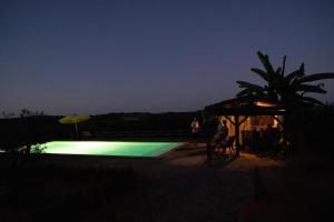 a swimming pool at night with people standing around it at Pure Gardères in Monlezun +47 photos