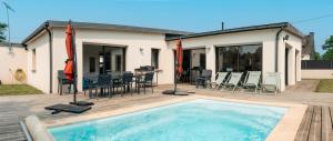 a swimming pool with chairs and a table and a house at Maison de Saint-Jean in Fouesnant