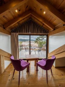 a room with purple chairs and a table and a large window at Hotel Quinta los Morales in San Cristóbal de Las Casas