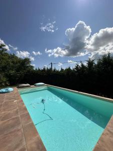 a blue swimming pool with a cloudy sky in the background at Le Chalet des Iris in Saint-Maurice-de-Gourdans