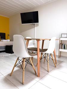 Una mesa de comedor con dos sillas blancas y un televisor. en Departamento El Olivo con cochera, en Santa Rosa 12 fotos más