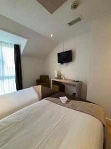 a hotel room with two beds and a flat screen tv at Hotel Herberg de Linden in Beneden-Leeuwen