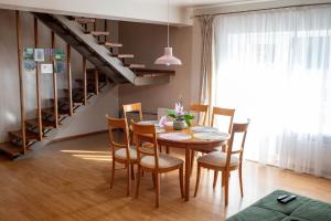 a dining room with a table and chairs and a staircase at Apartamentai Šilas in Druskininkai