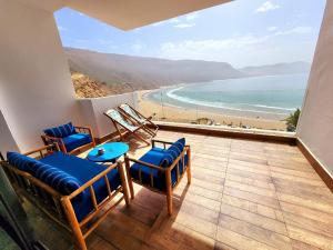 a balcony with chairs and a view of a beach at Aloha Imsouane vue sur mer in Imsouane