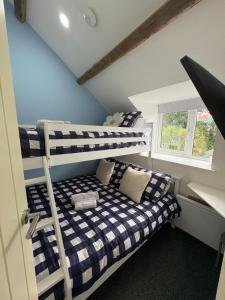 a room with two bunk beds and a window at Pauls Place - Festive Cottage with Hot Tub in Brynsiencyn