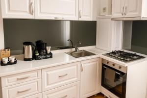 a kitchen with white cabinets and a sink and a stove at Mid Ultra Central Apartments, Self Check In in Oradea +82 photos