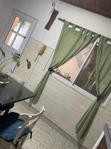 a room with a table and a window with green curtains at Antonia in San Nicolás de los Arroyos