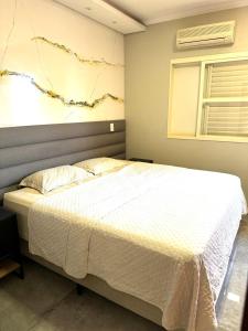 ein Schlafzimmer mit einem Bett mit einer weißen Tagesdecke in der Unterkunft Casa dos sonhos na Zona Sul in Ribeirão Preto