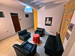 a living room with black leather furniture and a red table at Hotel C Villa Plaza in San Gil