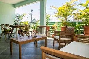 a patio with tables and chairs and palm trees at Les 3 Ti Fruits in Les Anses-dʼArlets